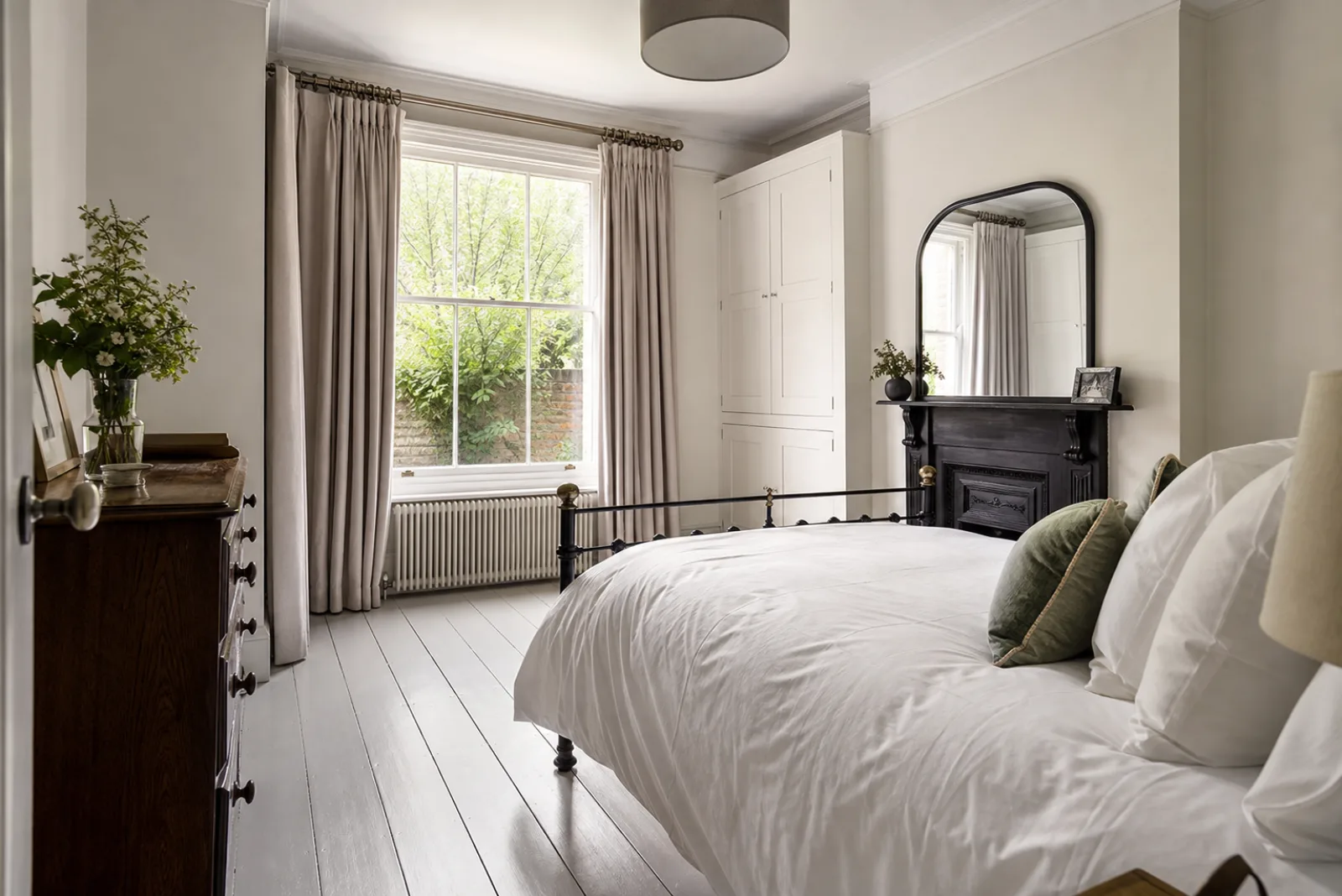 A freshly cleaned, spotless bedroom with painted floorboards and a neatly made bed in a British Victorian terraced house