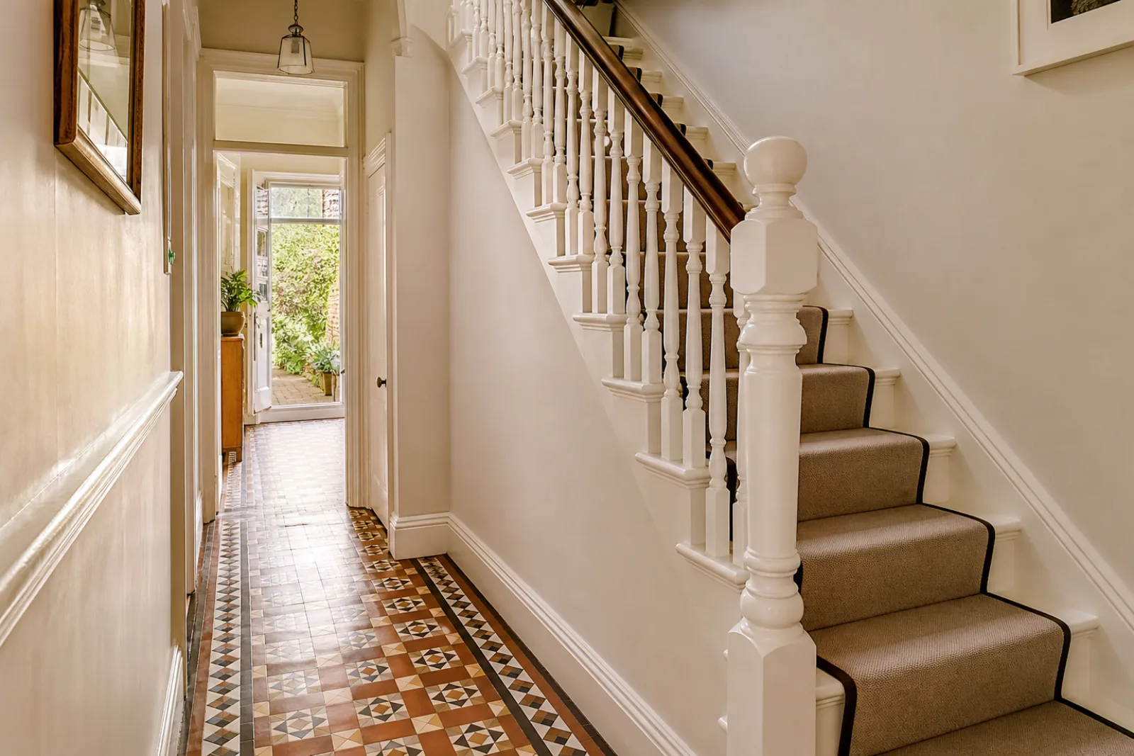 A freshly cleaned, spotless hallway with original tiled floor and white spindle staircase in a British Victorian terraced house