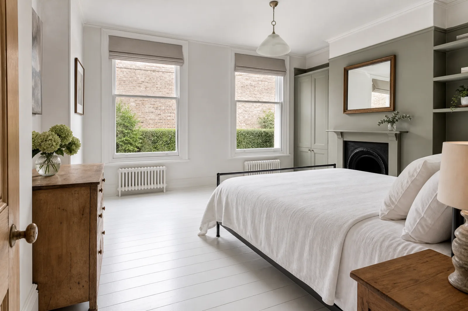 A freshly cleaned, spotless bedroom with painted floorboards and a neatly made bed in a British Victorian terraced house, bright overcast daylight, everything g