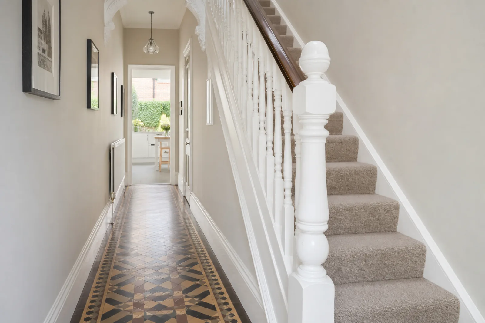 A pristine hallway with original tiled floor and white spindle staircase in a British Victorian terraced house just after a professional clean, bright overcast 