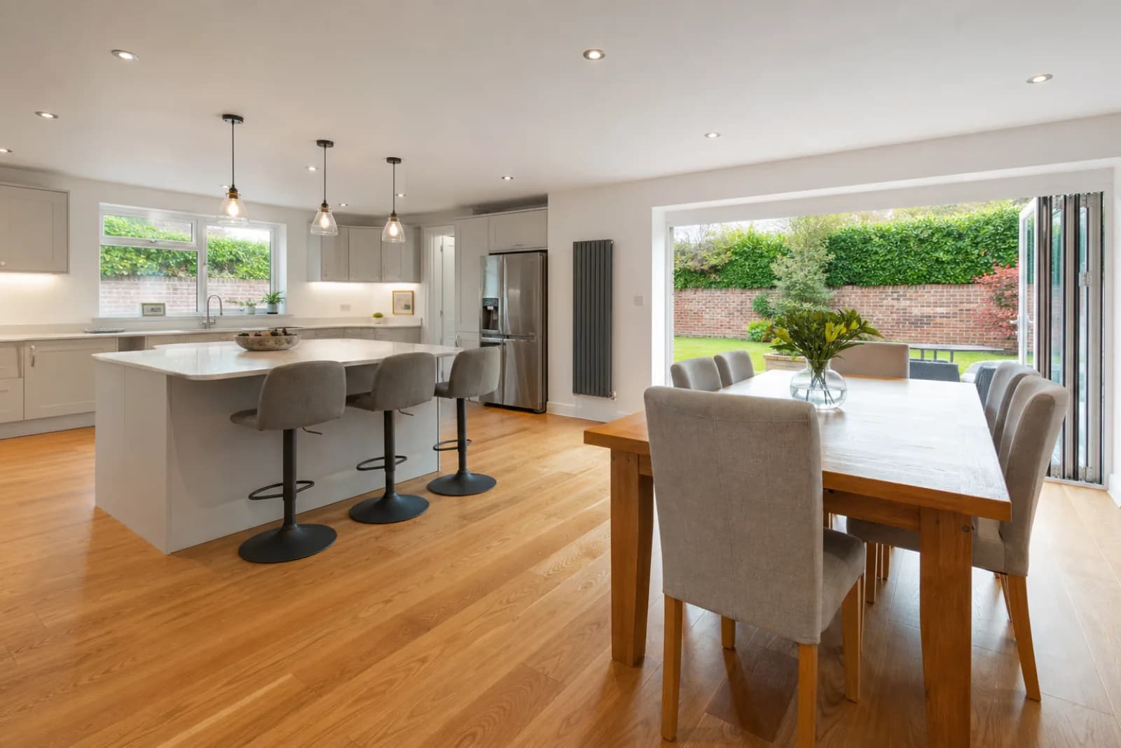 A freshly cleaned, spotless open-plan kitchen diner with oak flooring in a British detached family home, bright overcast daylight, everything gleaming and perfe