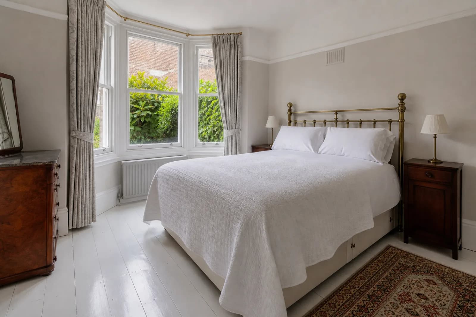 A freshly cleaned, spotless bedroom with painted floorboards and a neatly made bed in a British Victorian terraced house, bright overcast daylight, everything g