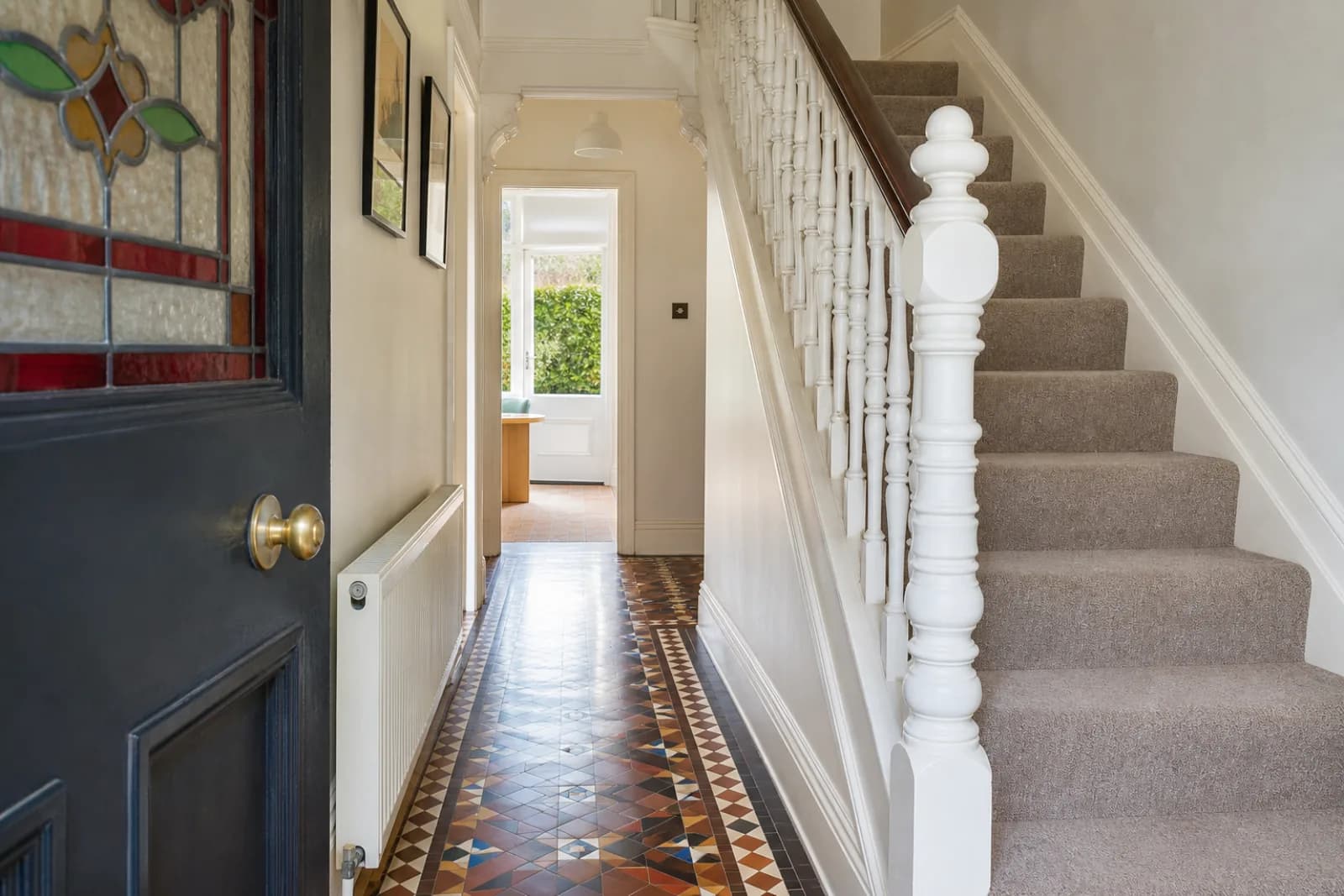 A pristine hallway with original tiled floor and white spindle staircase in a British Victorian terraced house just after a professional clean