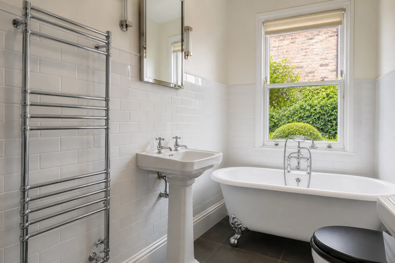 A pristine bathroom with white metro tiles and a gleaming chrome towel radiator in a British Edwardian semi-detached house just after a professional clean
