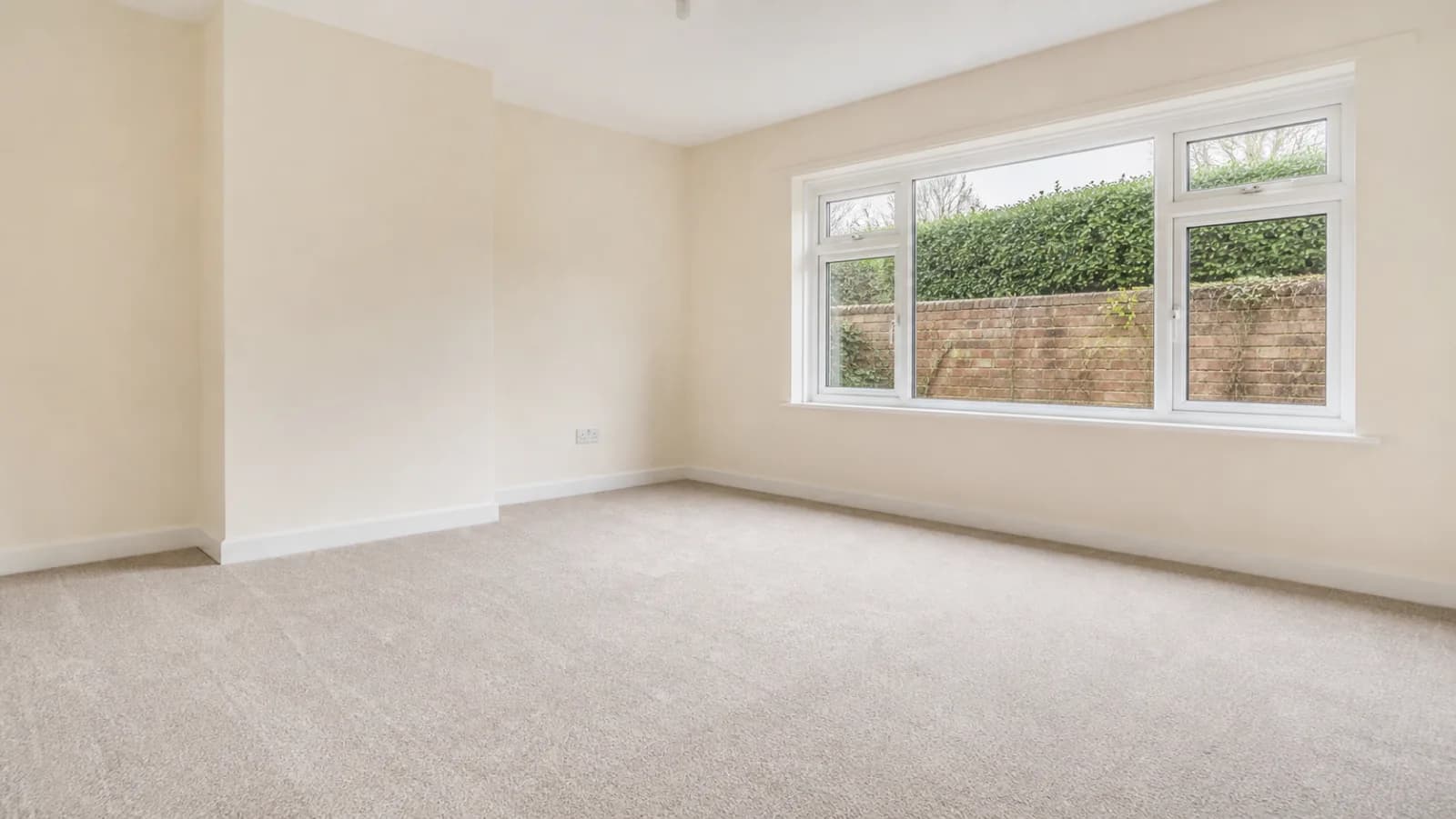 A completely empty, freshly cleaned British rental flat living room ready for checkout inspection, spotless carpet, clean walls, gleaming windows, bright overca